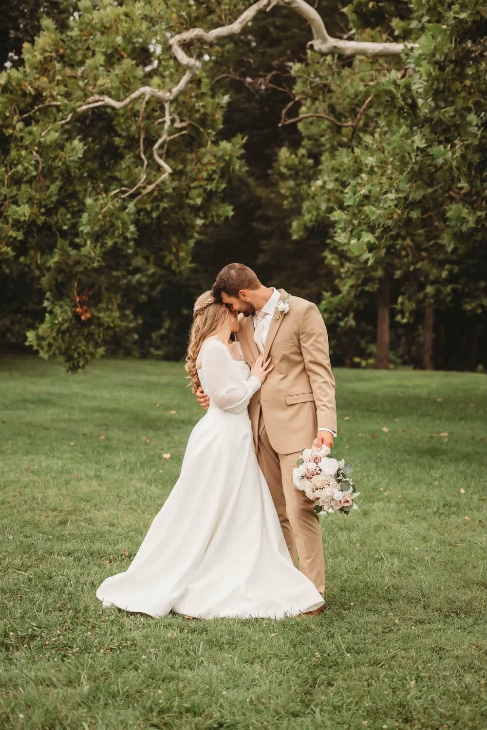 Amanda and Harlen leaning their foreheads together beneath leafy trees in Festus, Missouri.