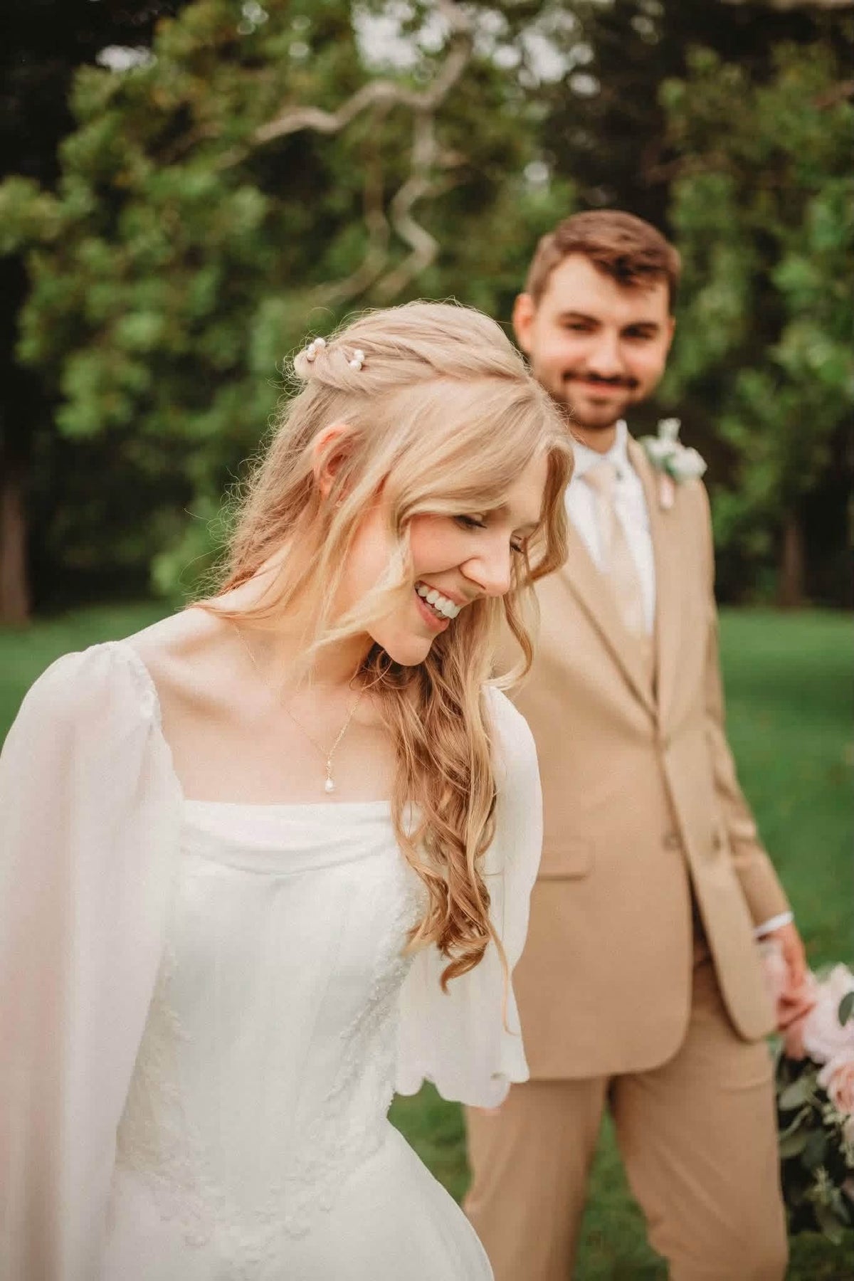 Amanda smiling in the foreground with Harlen standing behind her in his tan suit.