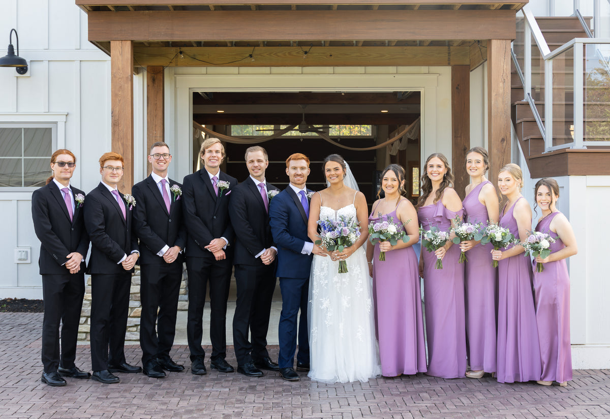 Amy and Jarrett with their wedding party outside a brick building.