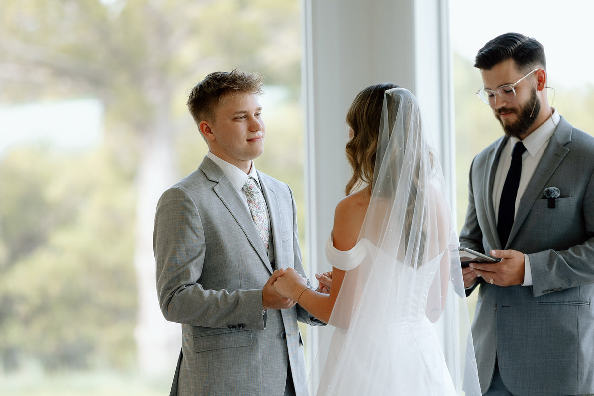 Ava and Ryan holding hands during their wedding ceremony.