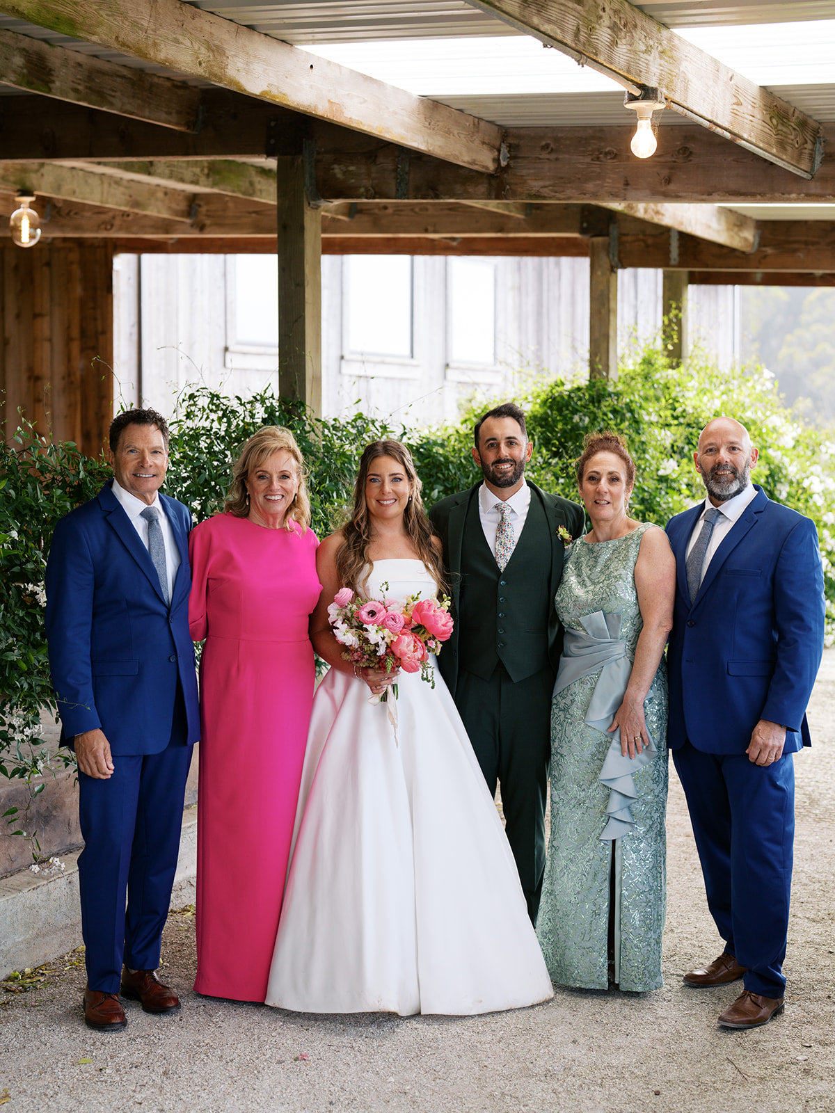 Danielle and Derick posing with four guests beneath a wooden shelter.