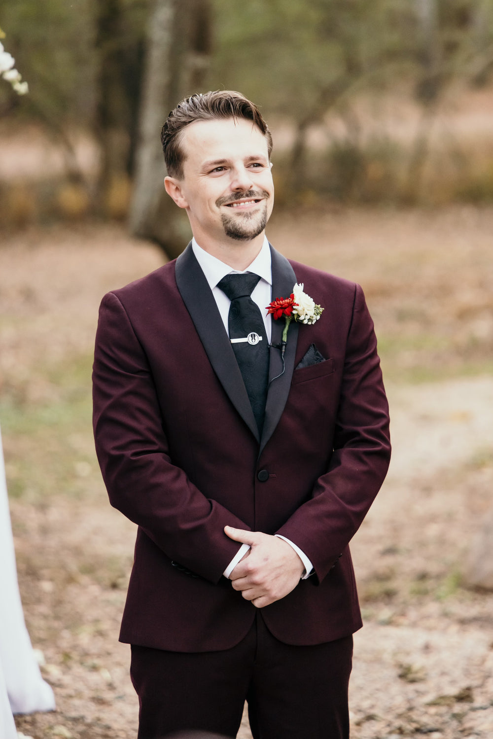 Nicolas wearing a burgundy tuxedo with black lapels and a black bow tie.