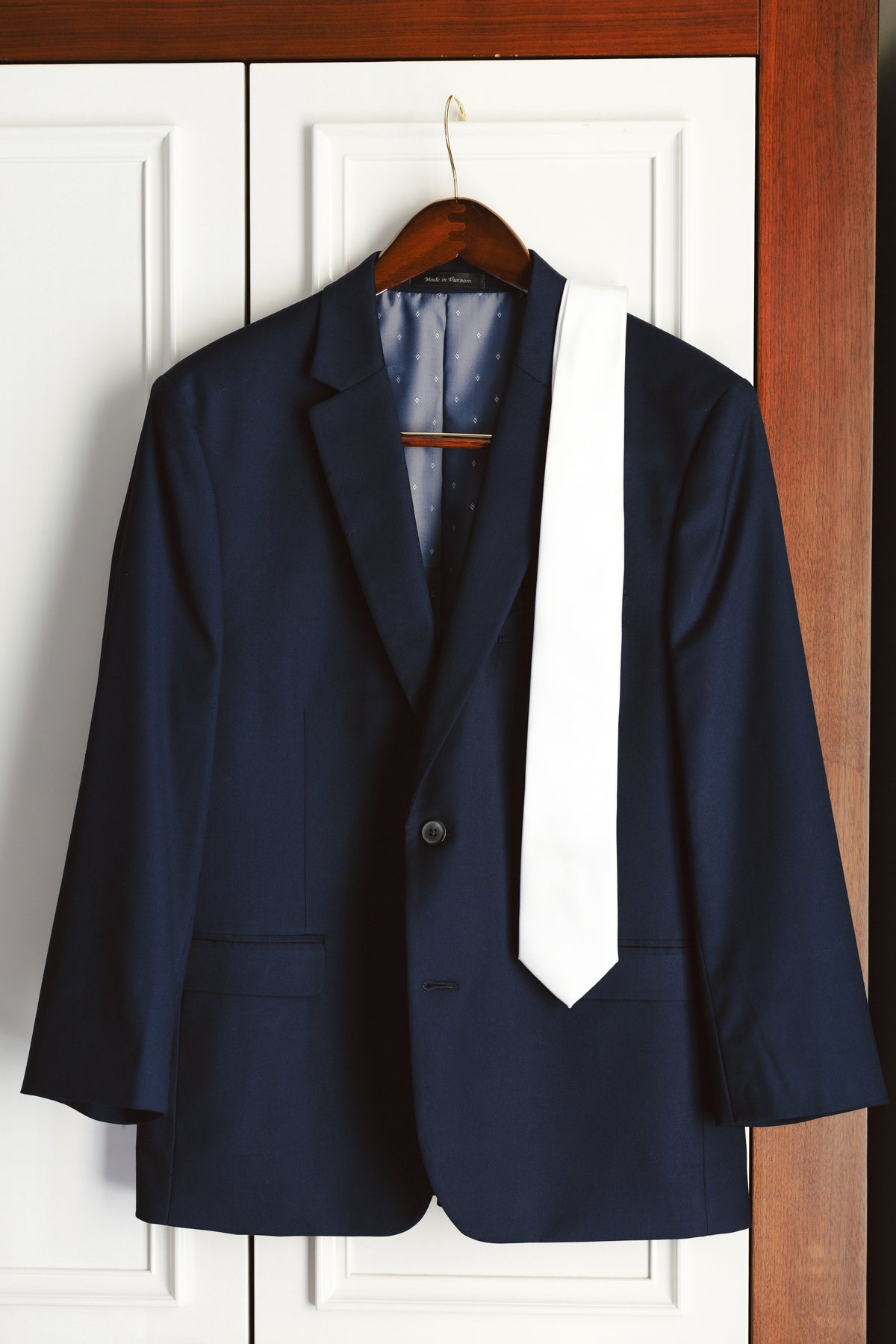 William’s navy suit jacket and white tie hanging before the wedding.