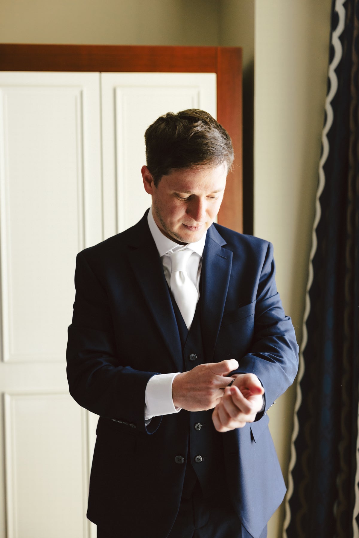 William getting ready in his navy three-piece suit.
