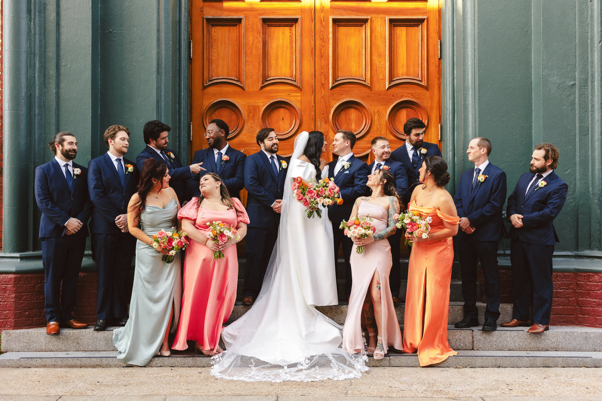 Kelsey and William with their wedding party in front of large wooden doors.