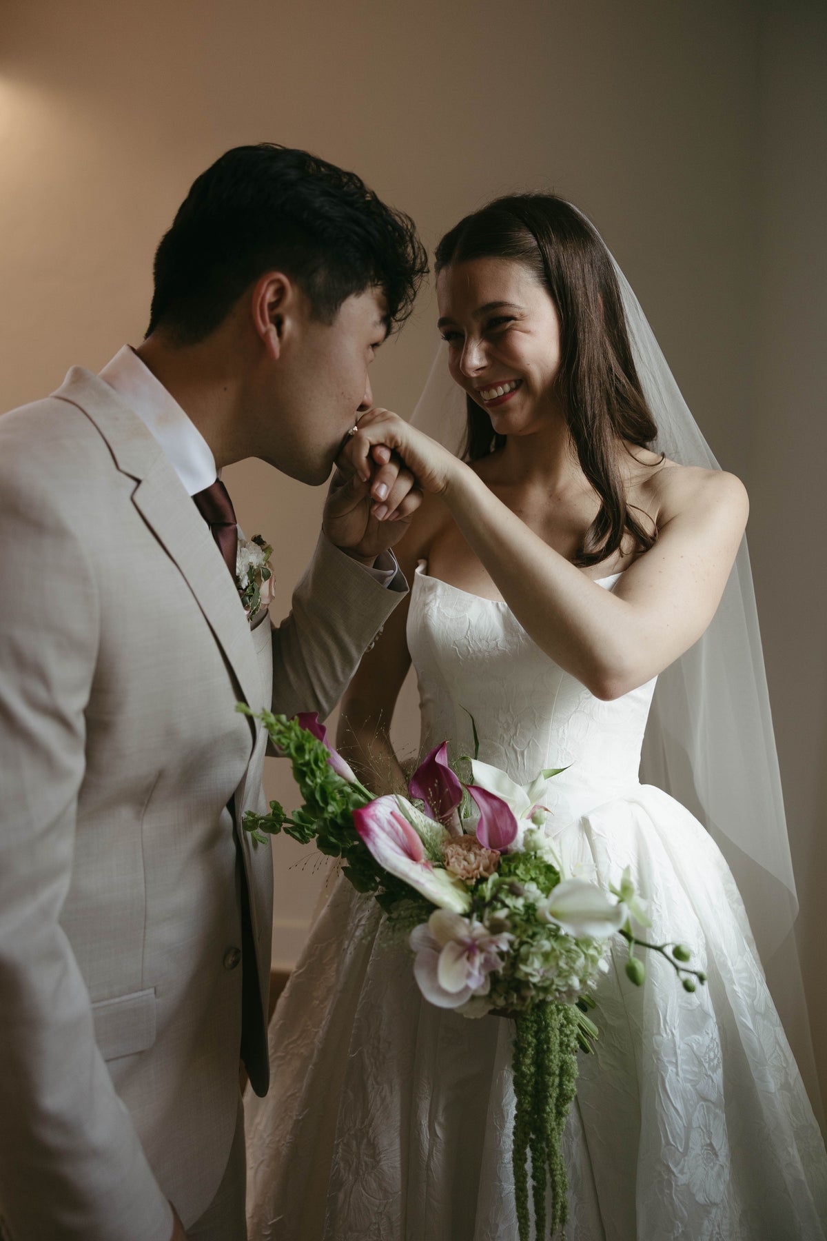 Andrew kissing Sophia’s hand as she holds her bridal bouquet.