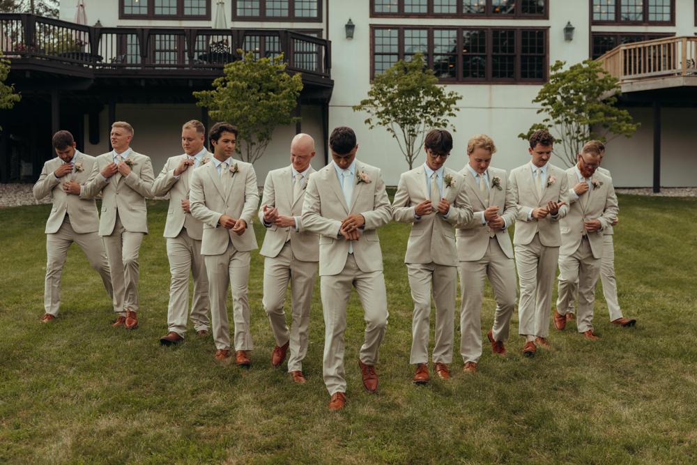 Men in beige suits standing in a line on grass