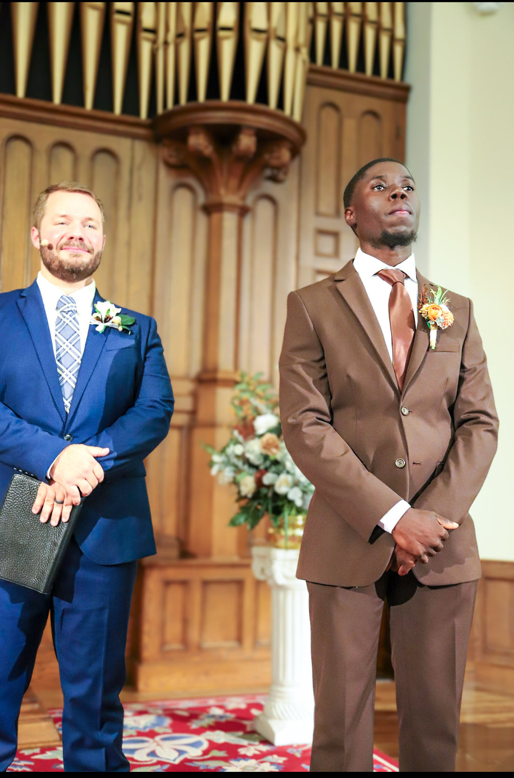 Dontavious standing in church wearing a chocolate suit and matching tie.