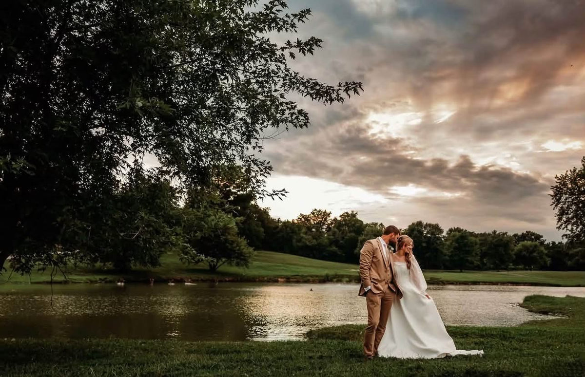 Amanda and Harlen beside a pond beneath a cloudy evening sky on their wedding day.