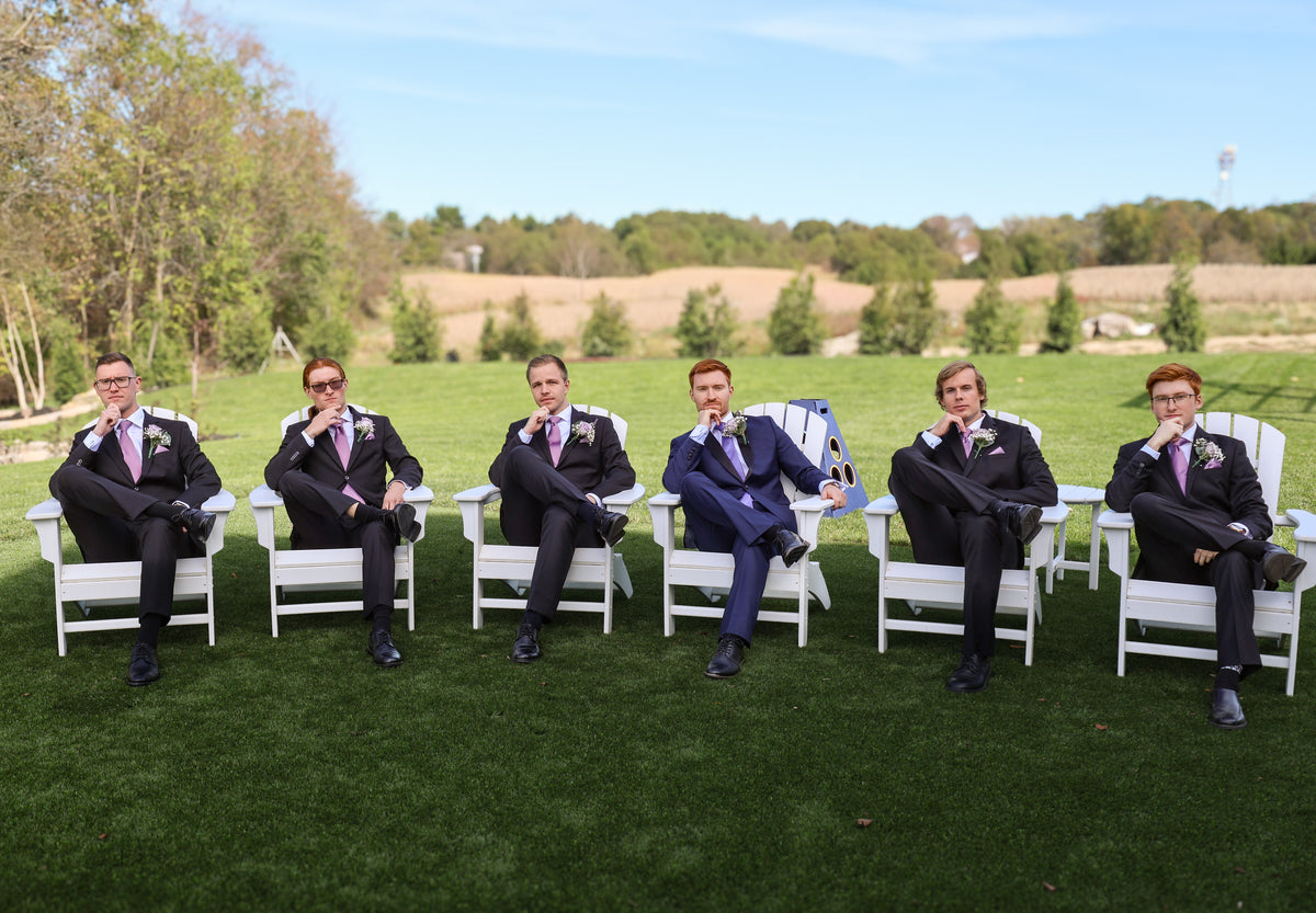 Jarrett and his groomsmen seated in white chairs outdoors.