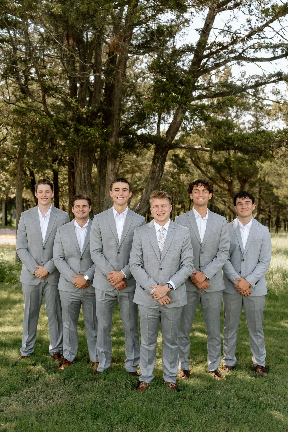 Ryan and his groomsmen in matching gray suits beneath a tree.