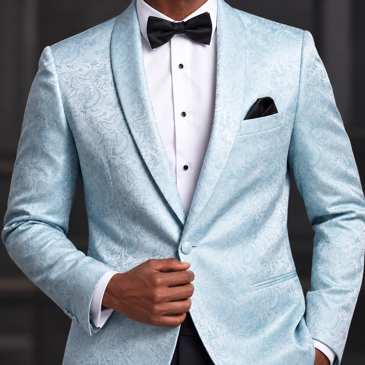A man wearing a light blue patterned tuxedo jacket with a white dress shirt, black bow tie, and black pocket square.