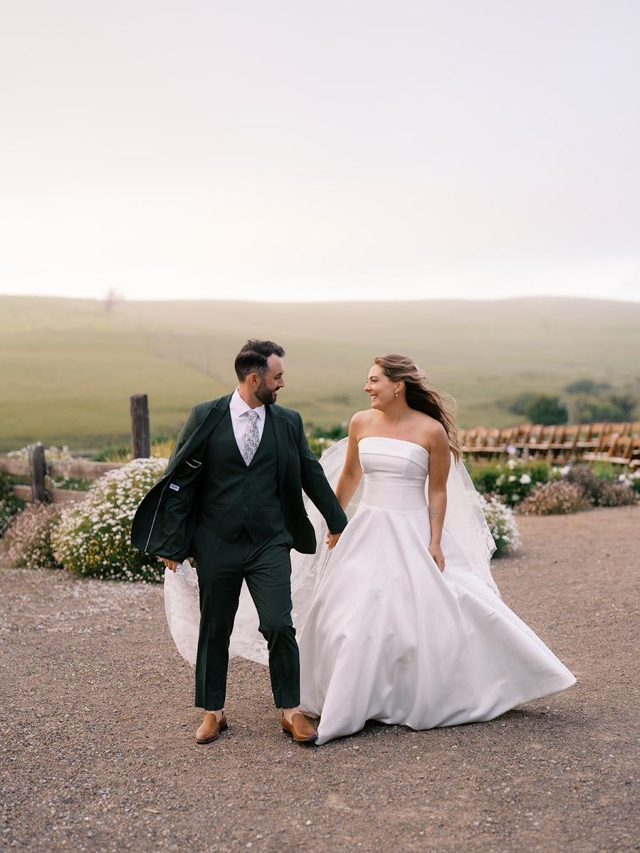 Danielle and Derick smiling at each other as they walk along a gravel path.