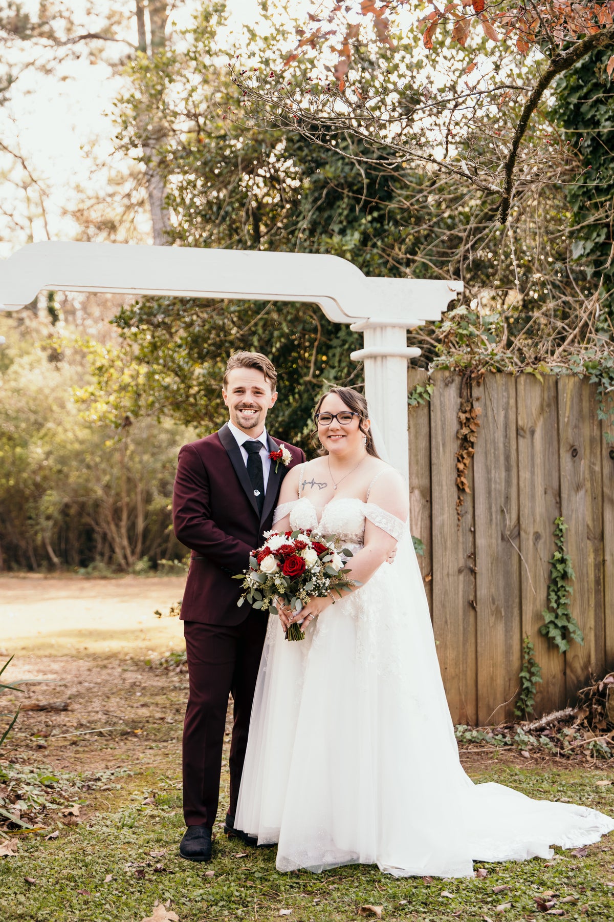 Diana and Nicolas standing beneath a white wedding arch.