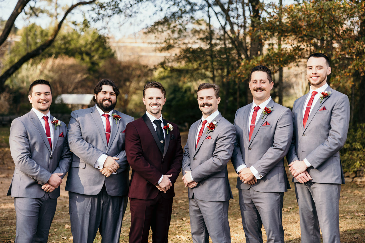Nicolas in a burgundy tuxedo with his groomsmen in gray suits.