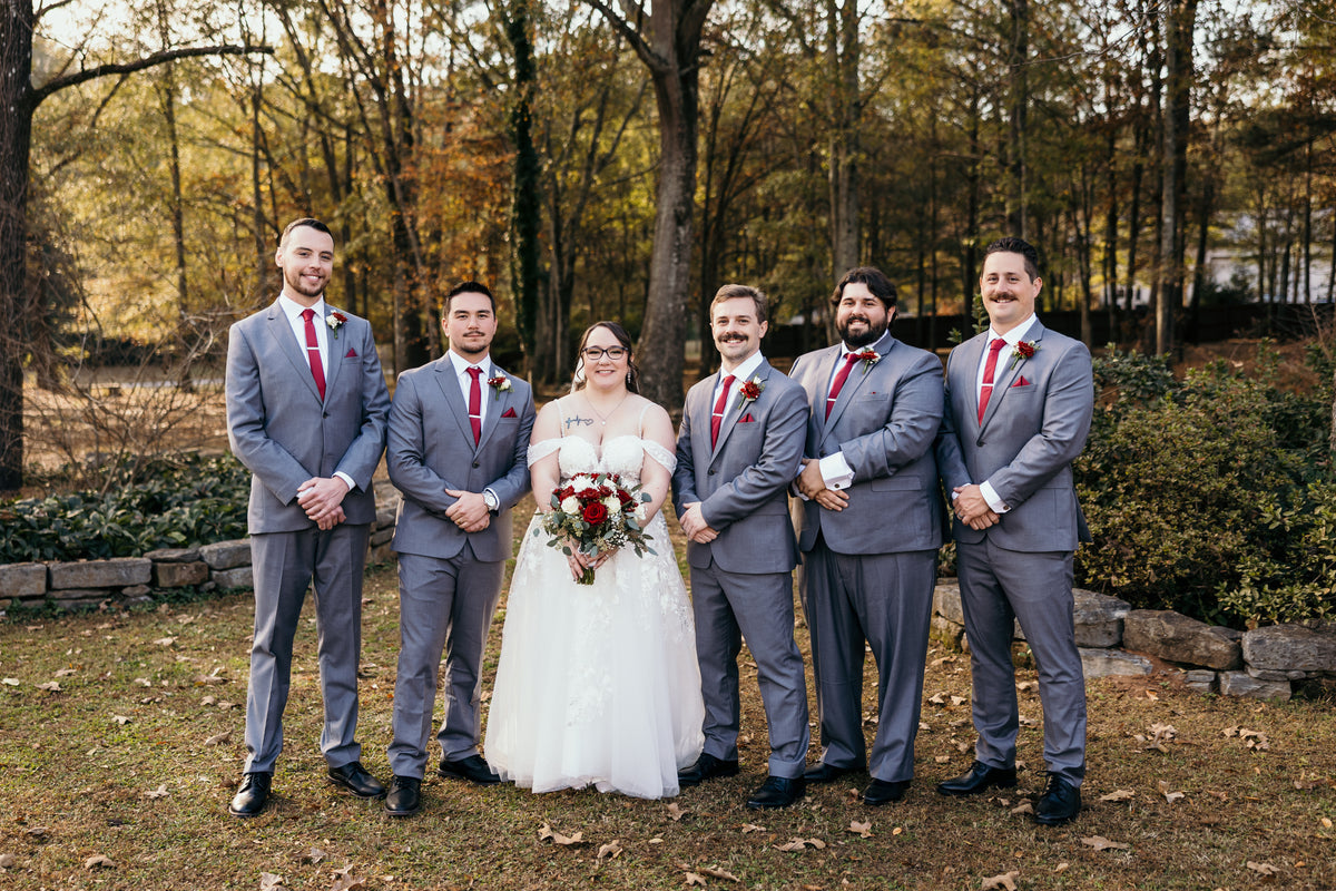 Diana posing with Nicolas and the groomsmen outdoors.