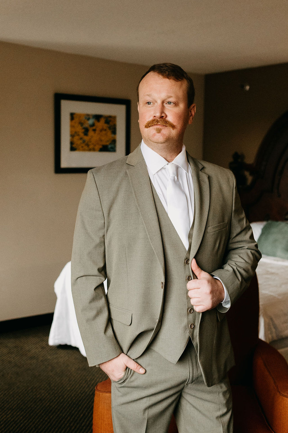 Kyle wearing a sage three-piece suit while getting ready for the wedding.