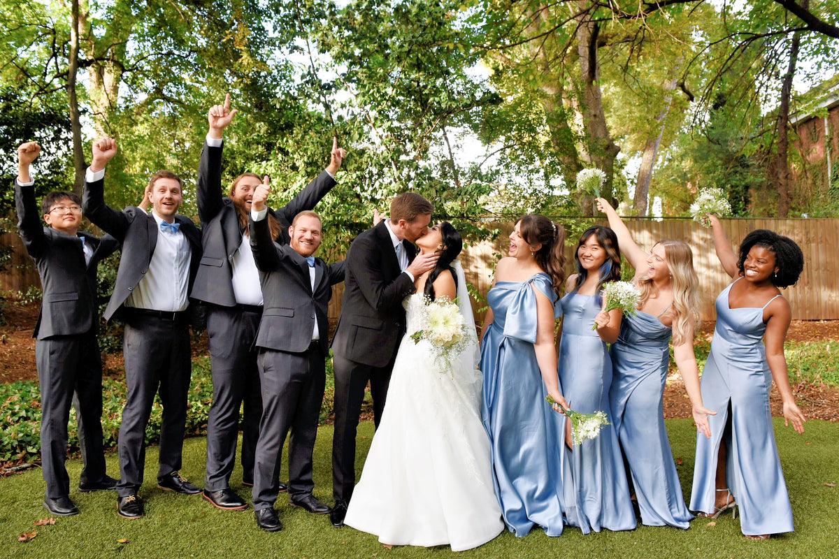 Justine and Austin celebrating with their wedding party beneath the trees.