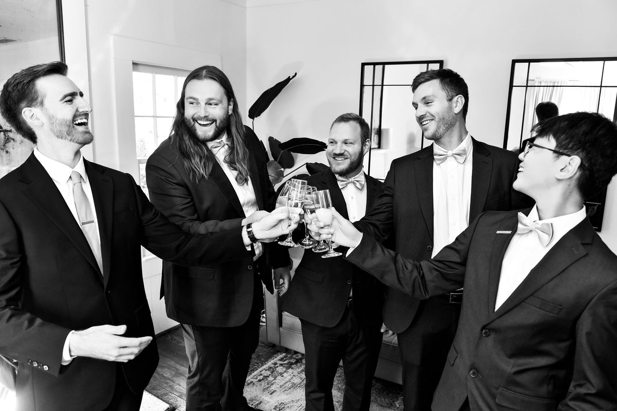 Black-and-white photograph of Austin and his groomsmen raising their glasses.