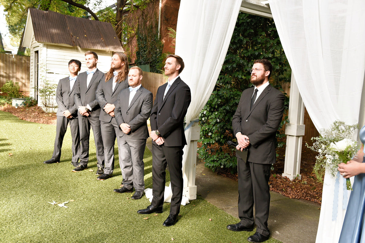 Austin and his groomsmen standing beside the outdoor ceremony arch.