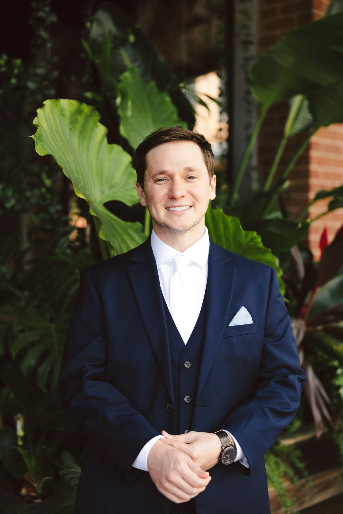 William posing outside in his navy suit, white tie, and white pocket square.