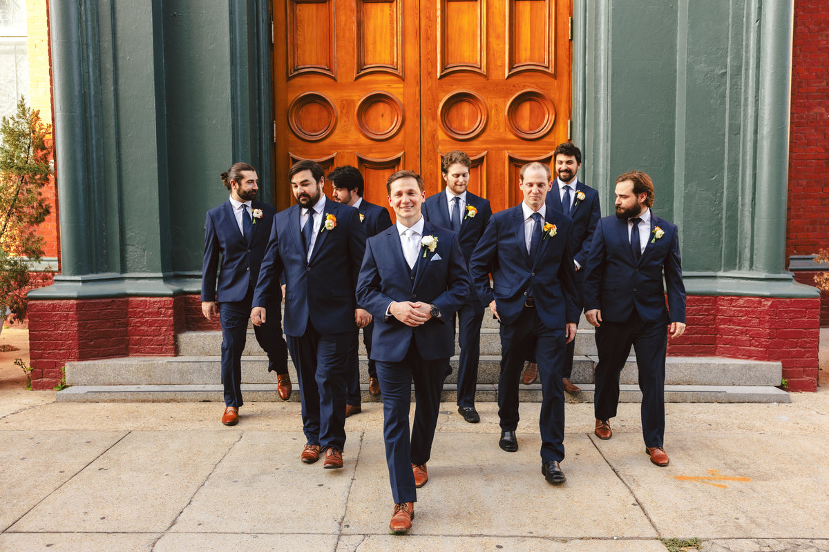 William and his groomsmen walking down the steps in navy suits.
