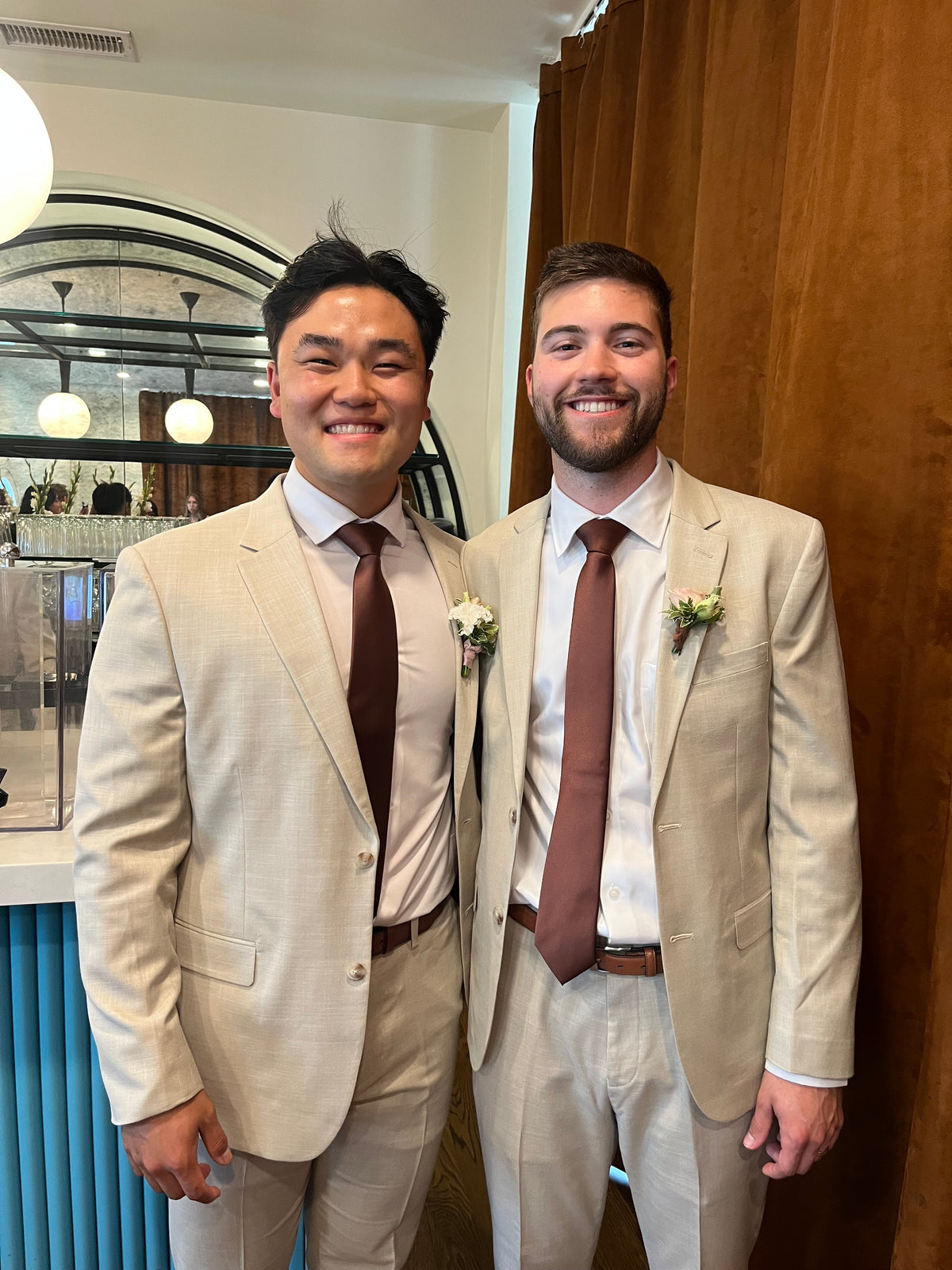 Andrew and a groomsman in tan suits and brown ties.